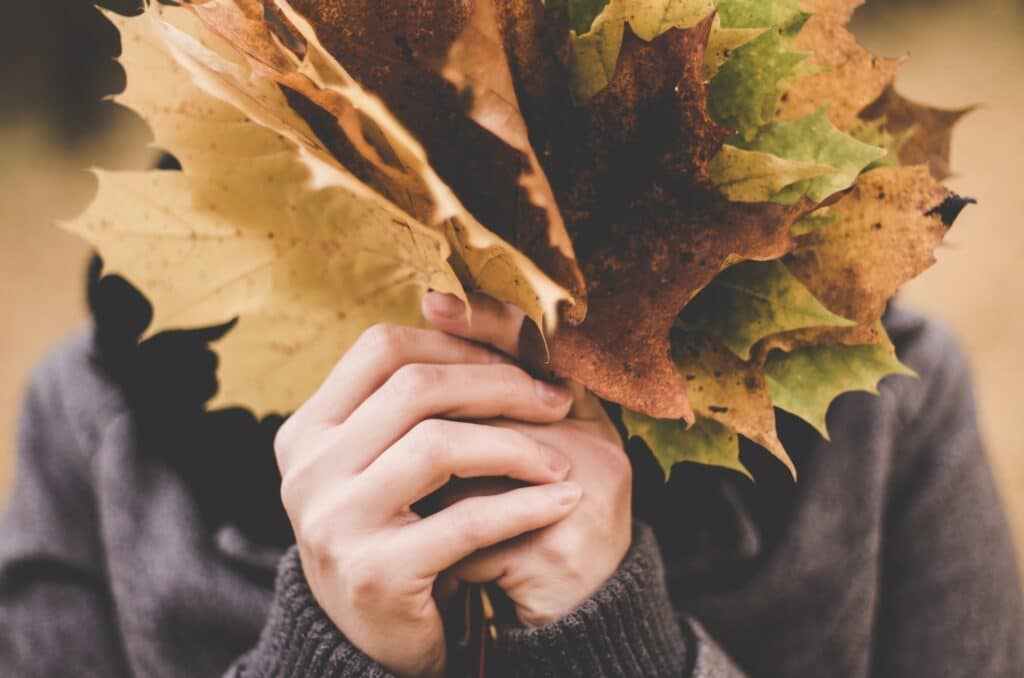 woman holds leaves in front of her face