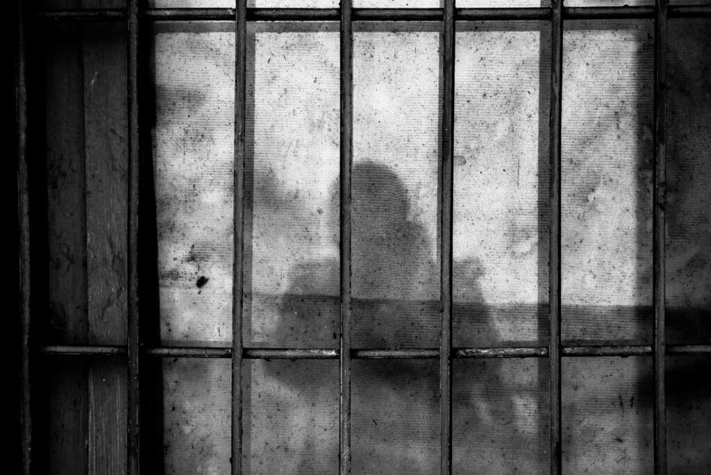 shadow of man over prison bars