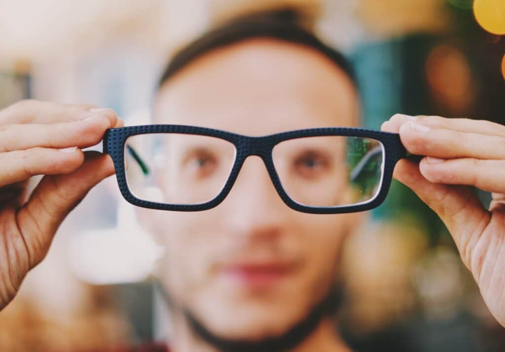 man holds glasses in front of his face