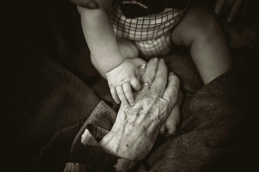 Elderly hand hold hand of a baby